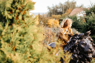 photo of a little girl in the park in autumn in nature riding a stone lion