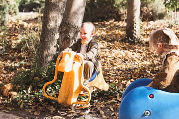 little kids brother and sister playing in the autumn in a beautiful amusement park
