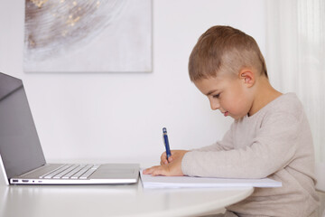 Little boy learning with a laptop at home. Online education and e-learning concept. Home quarantine...