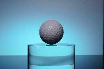 white golf ball on the transparent glass on color background