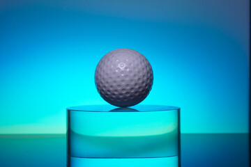 white golf ball on the transparent glass on color background