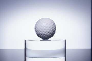 white golf ball on the transparent glass on color background