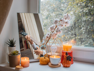 Girl sits in her room on a window sill decorated for the holiday and plays the ukulele. Her...