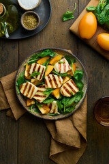 Tasty vegetarian healthy diet salad with orange tomatoes, grilled circassian halloumi cheese, fresh spinach, olive oil and condiment. Vertical, overhead