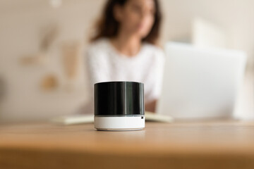 Close up of portable wireless speaker on desk of woman with laptop working or studying from home....