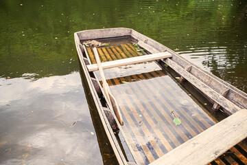 Abandoned wooden fishing boat on lake shore. Reflection on water surface.