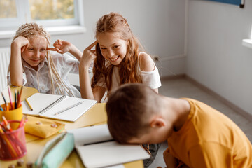 Happy girls joking at their classmate in class