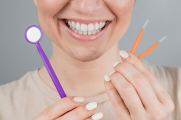 Close-up portrait of a smiling woman holding a brush and a dental mirror. Widescreen