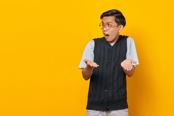 Portrait of asian man surprised with confused and displeased expression on yellow background