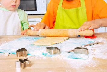 Close-up of children's hands roll dough with ram