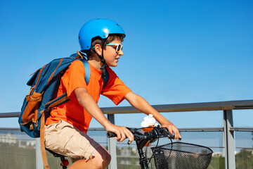 Side portrait of a boy with backpack on bicycle