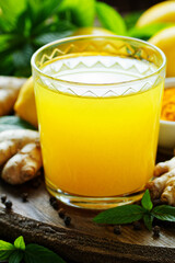Immune booster antivirus drink, turmeric with ginger, lemon, mint and spices hot winter tea on wooden rustic background, closeup, natural medicine and naturopathy concept