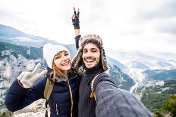 Fototapeta Traveler couple with backpacks taking selfie portrait hiking mountains - Happy guy and girl having fun outdoors obraz