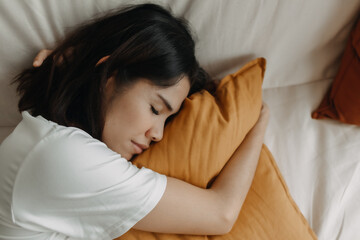 Asian woman is taking a nap or sleep on the sofa with yellow pillow.