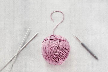 To knit or to crochet - that is the question. Ball of yarn, crochet hook and knitting needles spokes
