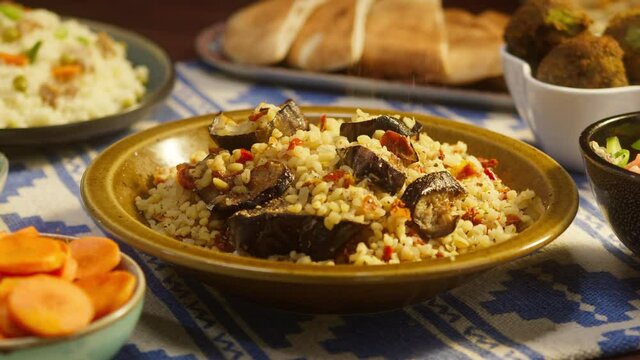 Sprinkling pepper on bulgur with eggplant close-up, couscous with meat on background. Traditional middle eastern culture. Delicious rice with meat. Arabian cuisine. Homemade food concept.