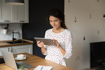 Happy female entrepreneur, employee, student with digital gadgets using online app on tablet for learning, accounting work, quick banking payment, shopping on internet, making video call
