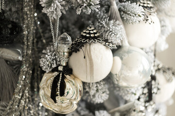 Close up of holidays location with jewelery toys and garlands on gray white Christmas tree