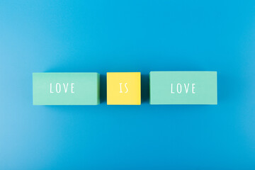 Love is love written on multicolored toy tablets on pink background