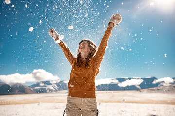 Fototapeta na wymiar Happy girl toss the snow in mountains