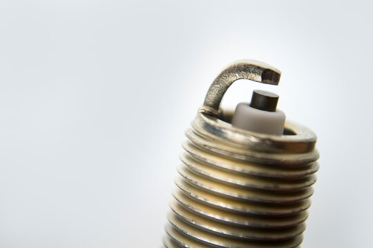 Auto service. New car spark plug as spare part of auto transportation on gray background.