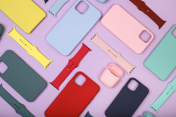 Colored silicone phone cases, complete with watch strap and case for headphones. Set. Up to date technology.Close up of diverse personal accessory laying on the lavender background. Flat lay - obrazy, fototapety, plakaty