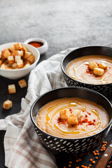Lentil cream soup with paprika and crouton in black ceramic bowls