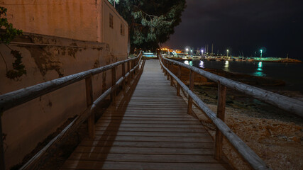 Pasalera de madera sobre las rocas y junto al mar en la playa de la Albufereta por la noche en Alicante