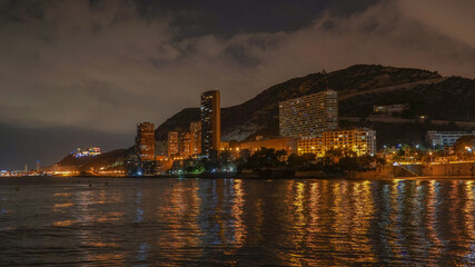Fototapeta na wymiar Panorámica nocturna de las calitas de la Playa de la Albufereta y sus rascacielos con reflejos en el mar