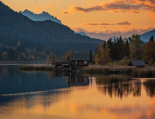 Weissensee, Austria small wooden boat house reflected in the lake at sunset