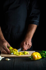Cook cutting bell peppers for salad in the restaurant kitchen. Close-up of a chef hands while working