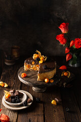 Fototapeta premium Delicious chocolate cake with physalis,blackberries,roses,vintage dishes on wooden background in rustic style.Still life with dessert in autumn colors.