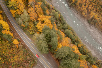 Overhead View of an Automobile Traveling on a Roadway Next to a River During the Fall Season. A car travels along the colorful, autumnal, Mt. Baker Highway alongside the beautiful Nooksack River. 