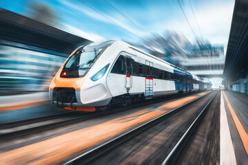 Fototapeta na wymiar High speed train in motion on the railway station at sunset