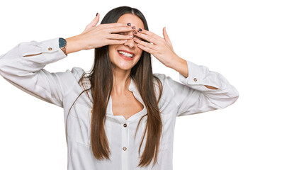 Young beautiful woman wearing casual white shirt covering eyes with hands smiling cheerful and funny. blind concept.