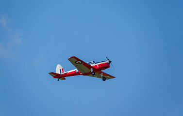Fototapeta na wymiar a 1951 De Havilland DHC-1 Chipmunk WD363 22 C-N C1-0304 flies low overhead in a deep blue autumn sky