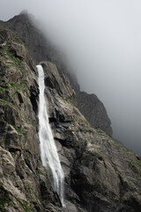 Beautiful view of Midagrabin waterfall in sunlight in cloudy summer weather. Caucasus mountains. Russia. North Ossetia Alania