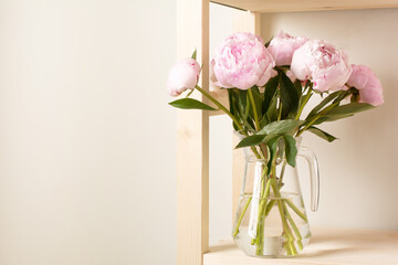 bouquet of fresh pink peonies in a glass vase on a shelf. holiday and gifts concept