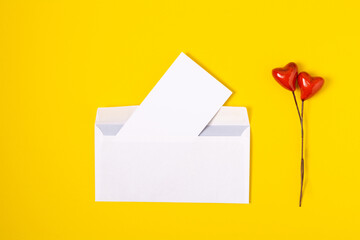 top view love letter, white envelope and card with red hearts on yellow background. white letter...