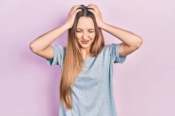 Young blonde girl wearing casual t shirt suffering from headache desperate and stressed because pain and migraine. hands on head.