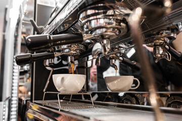 Pouring coffee stream from professional machine in cup. Barista making espresso, using filter holder. Flowing fresh ground coffee. Drinking roasted black coffee in the morning.