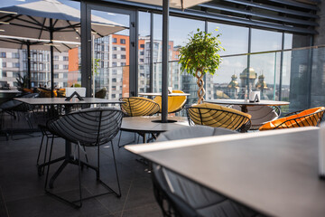 Bright garden furniture and plants on cozy terrace with wooden floor and brick wall. Interior of a summer terrace of a restaurant