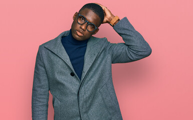 Fototapeta premium Young african american man wearing business clothes and glasses confuse and wondering about question. uncertain with doubt, thinking with hand on head. pensive concept.