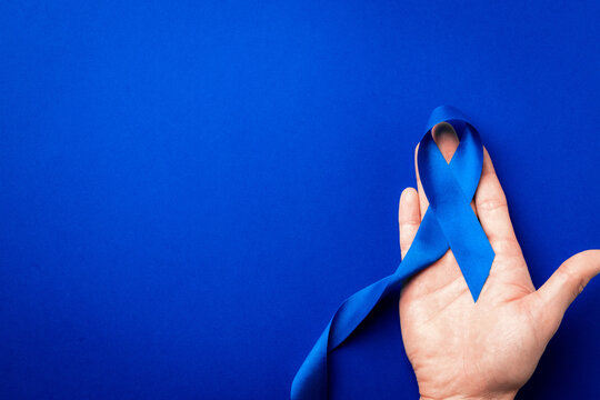 Prostate care. Awareness prostate cancer of men health in November. Blue ribbon in hands isolated on deep blue background. World cancer day and world diabetes day concept.
