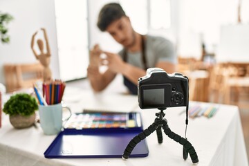 Young hispanic artist man smiling happy making online art class at studio.