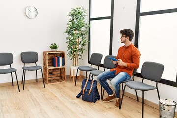 Young hispanic man using touchpad at waiting room