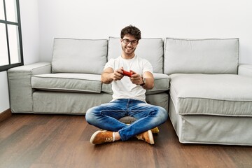 Fototapeta na wymiar Young hispanic man smiling confident playing video game at home
