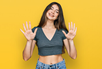 Young beautiful teen girl wearing casual crop top t shirt showing and pointing up with fingers number ten while smiling confident and happy.