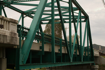 Fototapeta premium Green painted steel bridge over a stream