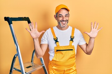 Handsome middle age man with grey hair holding ladder showing and pointing up with fingers number ten while smiling confident and happy.